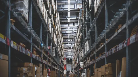 Long warehouse aisle with tall shelves stacked with boxes, typical of fulfillment work