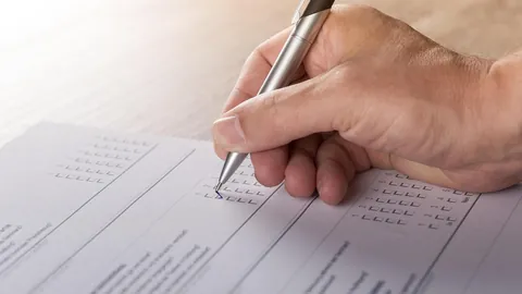 يد تملأ نموذجا مطبوعا بقلم، كما يحدث عند تعبئة نموذج سيرة ذاتية جاهز