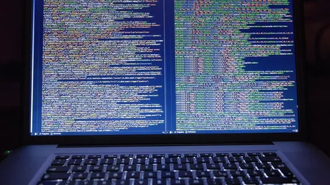 Laptop screen filled with lines of source code in a dark room, showing everyday programming work