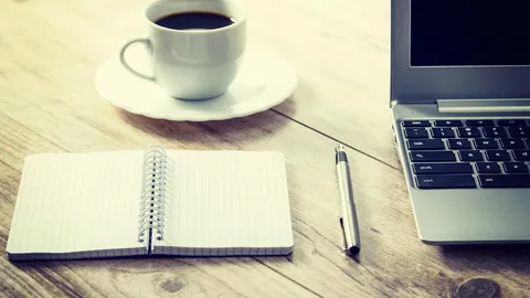 Open notebook, pen and coffee beside a laptop, ready to prepare answers for interview questions
