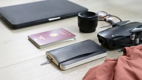 Passport, laptop, notebook and camera laid out on a table ready for a nomad trip