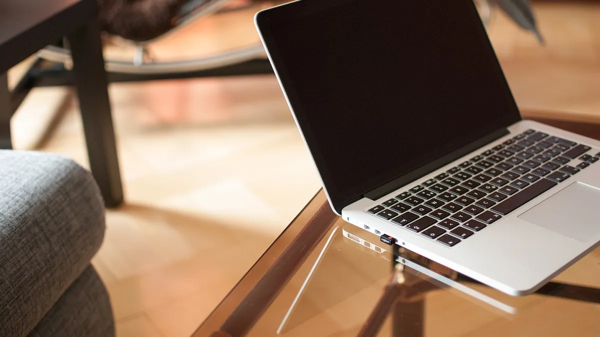 Laptop abierta sobre una mesa de cristal en casa, preparada para trabajar por internet