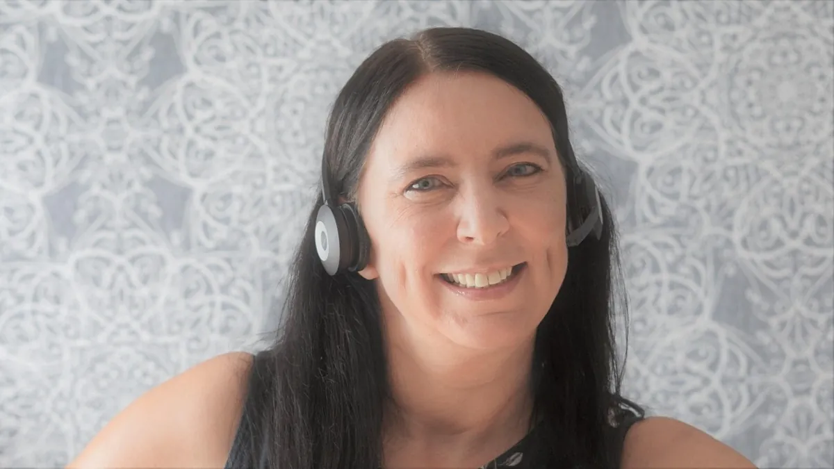Mujer sonriente con auriculares y micrófono, lista para atender llamadas en inglés