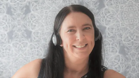 Mujer sonriente con auriculares y micrófono, lista para atender llamadas en inglés
