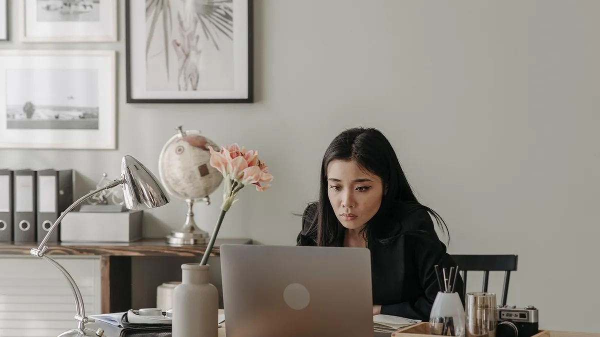 Mujer trabajando con su laptop en un escritorio de casa, lista para el trabajo remoto