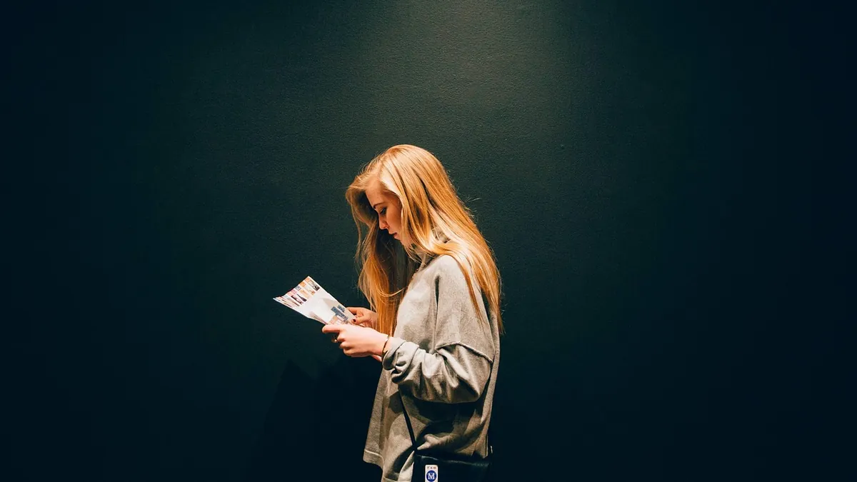 Jeune femme qui relit attentivement une feuille imprimée avant d'envoyer sa candidature