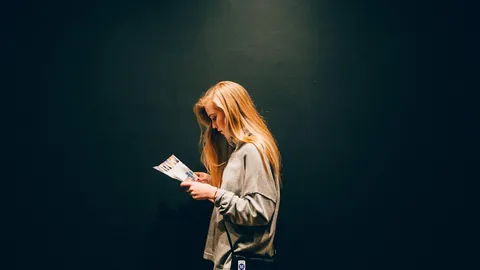 Jeune femme qui relit attentivement une feuille imprimée avant d'envoyer sa candidature