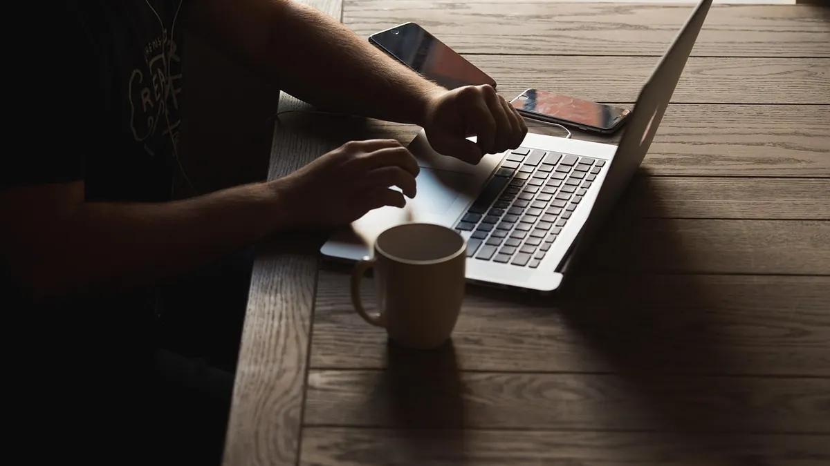Personne tapant sur un ordinateur portable à son bureau pour rédiger une lettre de motivation