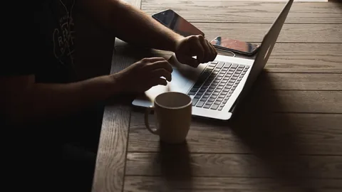 Personne tapant sur un ordinateur portable à son bureau pour rédiger une lettre de motivation