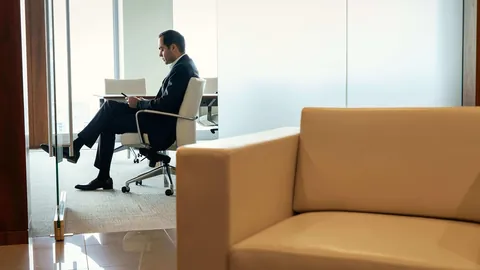 Homme en costume assis dans le hall lumineux d'une entreprise, une tenue classique pour un entretien d'embauche