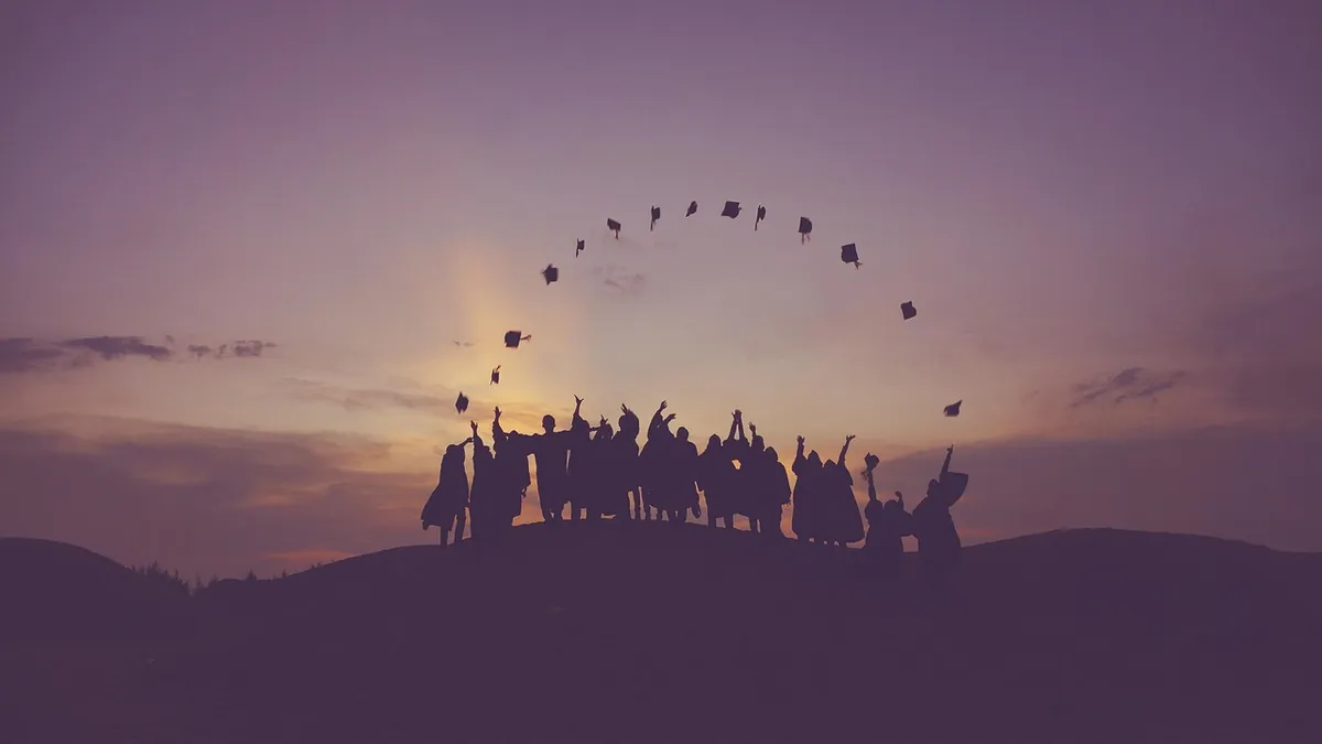 Silhouettes of new graduates throwing their caps at sunset, ready for their first job interviews