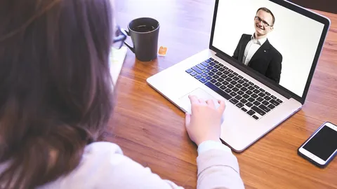 Candidate in a video interview with an interviewer on a laptop screen at a desk