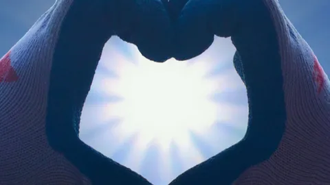 Gloved hands forming a heart against the sun, a symbol of nonprofit work
