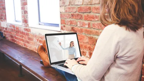 Estudante usando o notebook em casa junto a uma parede de tijolos para estudar e escrever
