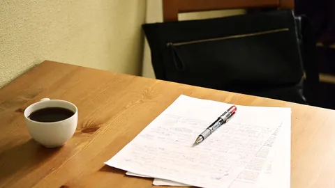 Folhas impressas, uma caneta e uma xícara de café sobre a mesa, prontas para revisar o currículo