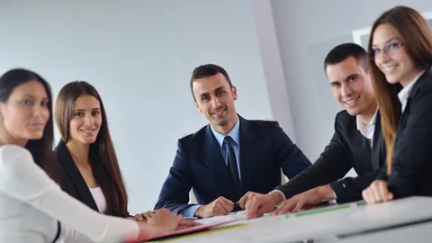 Equipe de colegas sorridentes reunida em volta de uma mesa de reunião no escritório