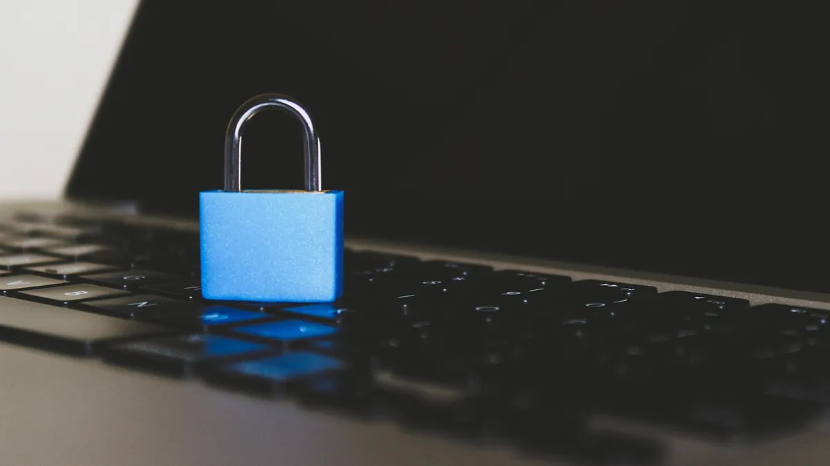 Blue padlock resting on a laptop keyboard, representing data security and cybersecurity work