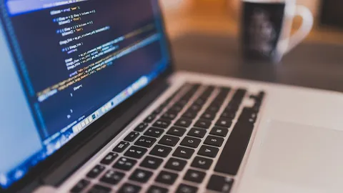 Laptop showing lines of code on a desk with a coffee mug, a software engineer workspace