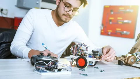 Young engineer assembling a small robot at his workbench, showing practical technical skills