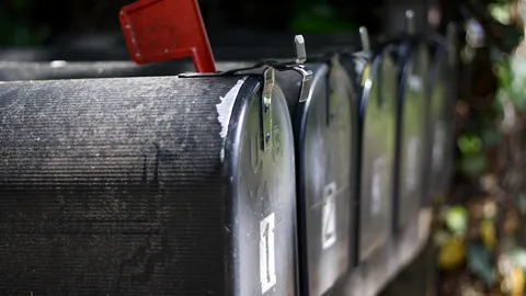 Row of black curbside mailboxes with a raised red flag along a residential street