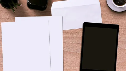 Blank sheets, an envelope and a tablet on a wooden desk, ready for a cover letter
